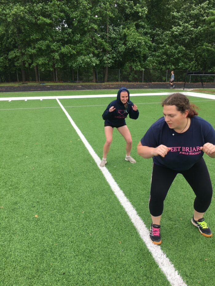 Two women athletes practice on a field.