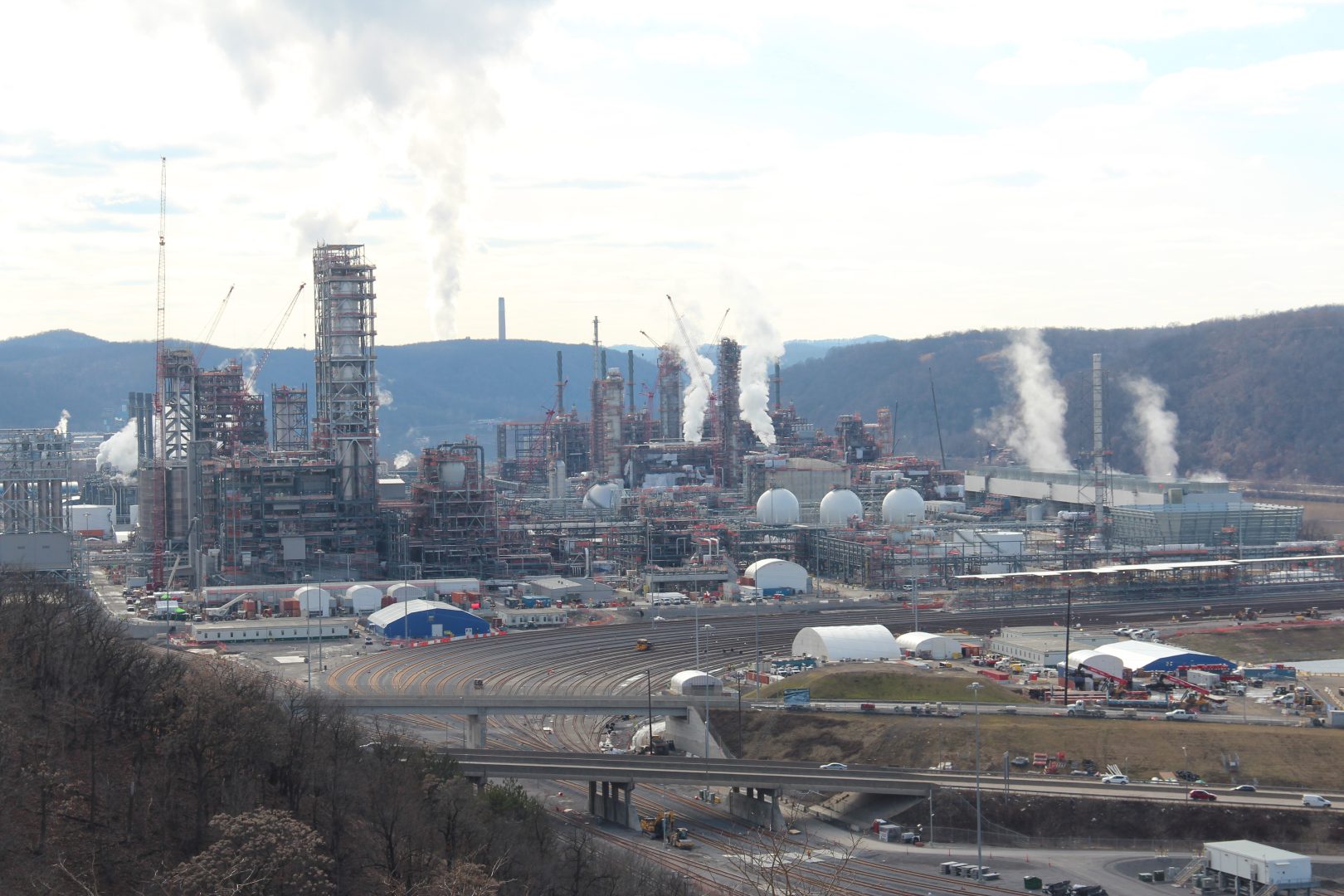 A sprawling industrial facility emits various substances into the air on a cloudy winter day.