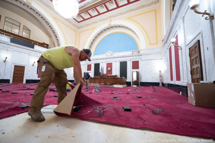 male worker in large chamber pulling up red carpet