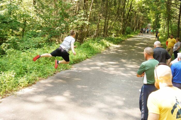 A man is seen mid-air after tossing an Irish Road Bowling ball.