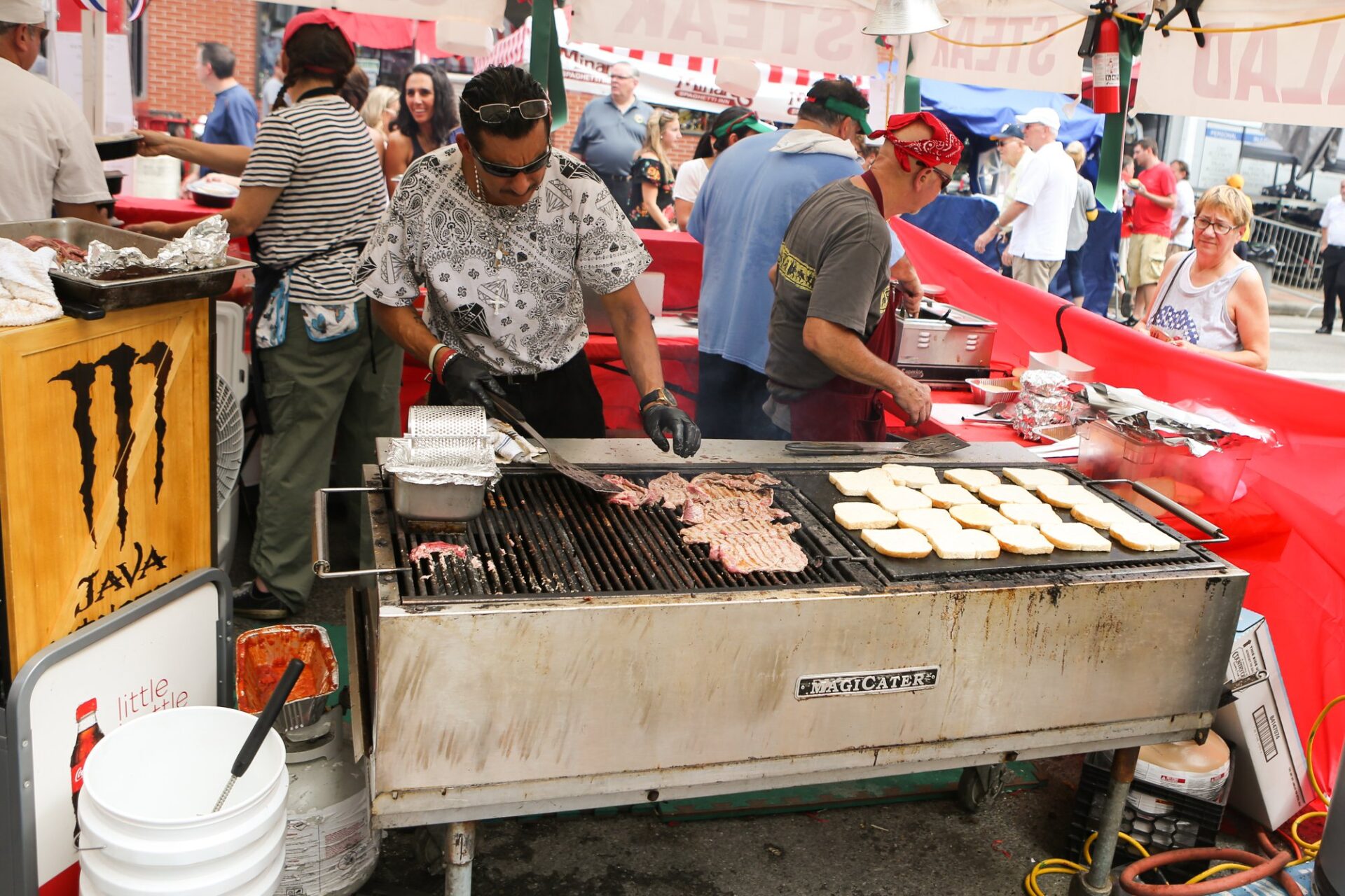 A man standing next to a grill cooking food.