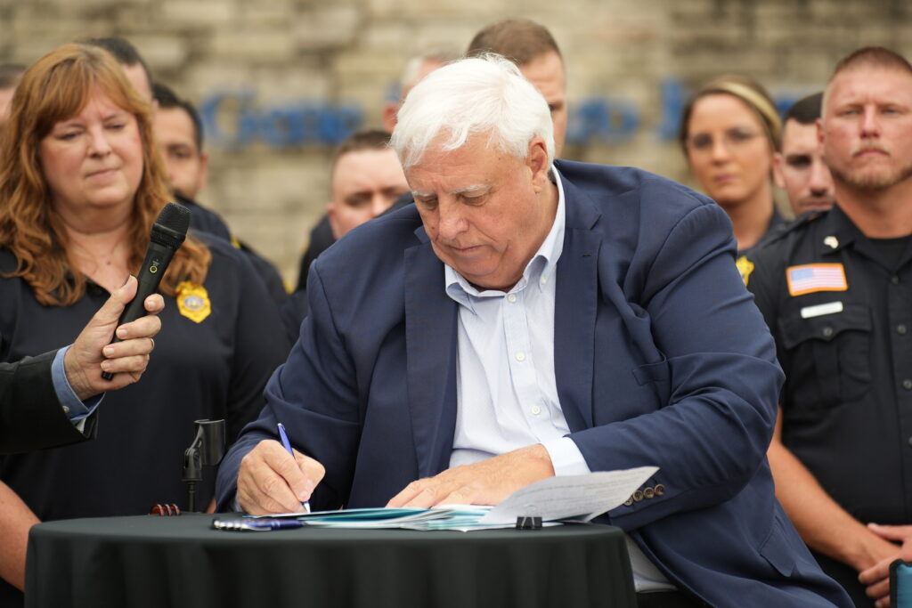 Big man with white hair signing a paper