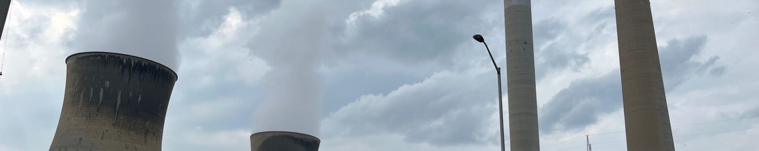 The Mitchell Plant's cooling towers and exhaust stack send columns of steam and carbon dioxide into the atmosphere on an overcast summer day.