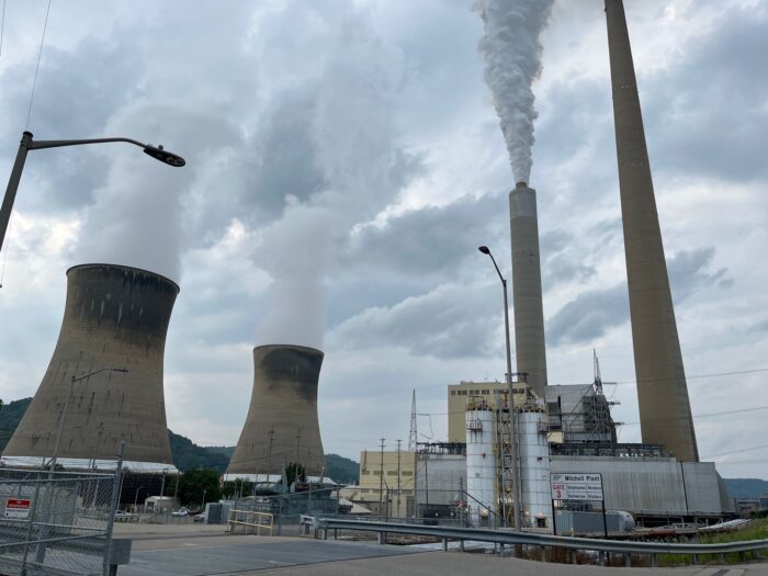 The Mitchell Plant's cooling towers and exhaust stack send columns of steam and carbon dioxide into the atmosphere on an overcast summer day.