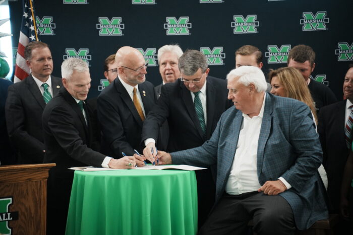 Several men in suits signing a bill into law