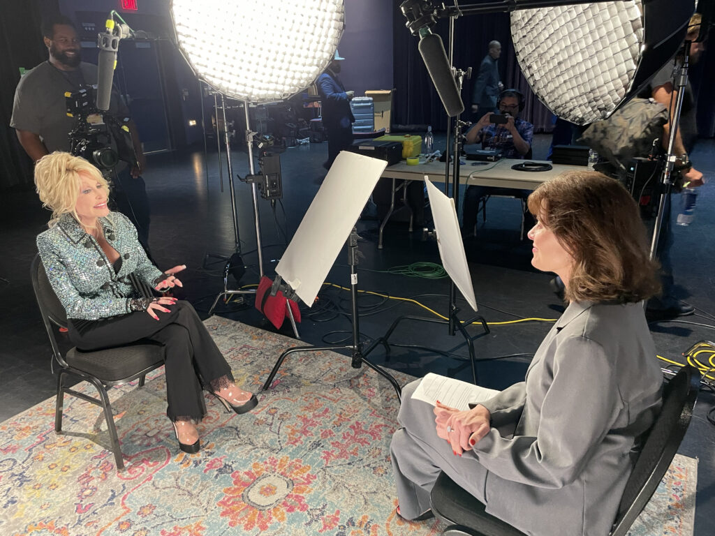 Two women speak in an interview, under studio lights.