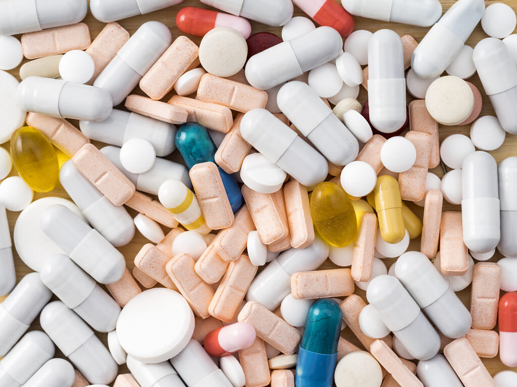 Assorted pills are seen laying in a pile.