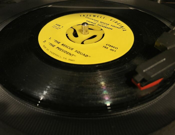 A record is shown in a record player. It reads "Tazewell, Virginia" and features two songs, 1. The Rescue Squad and 2. The President.