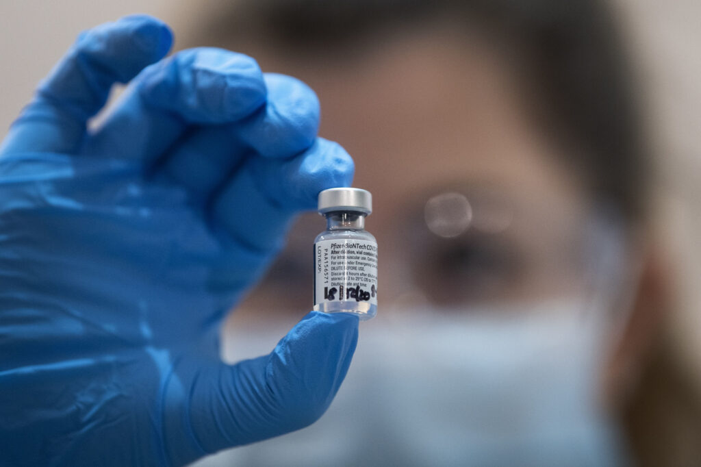 A physician holds up a vial of a COVID-19 Vaccine.
