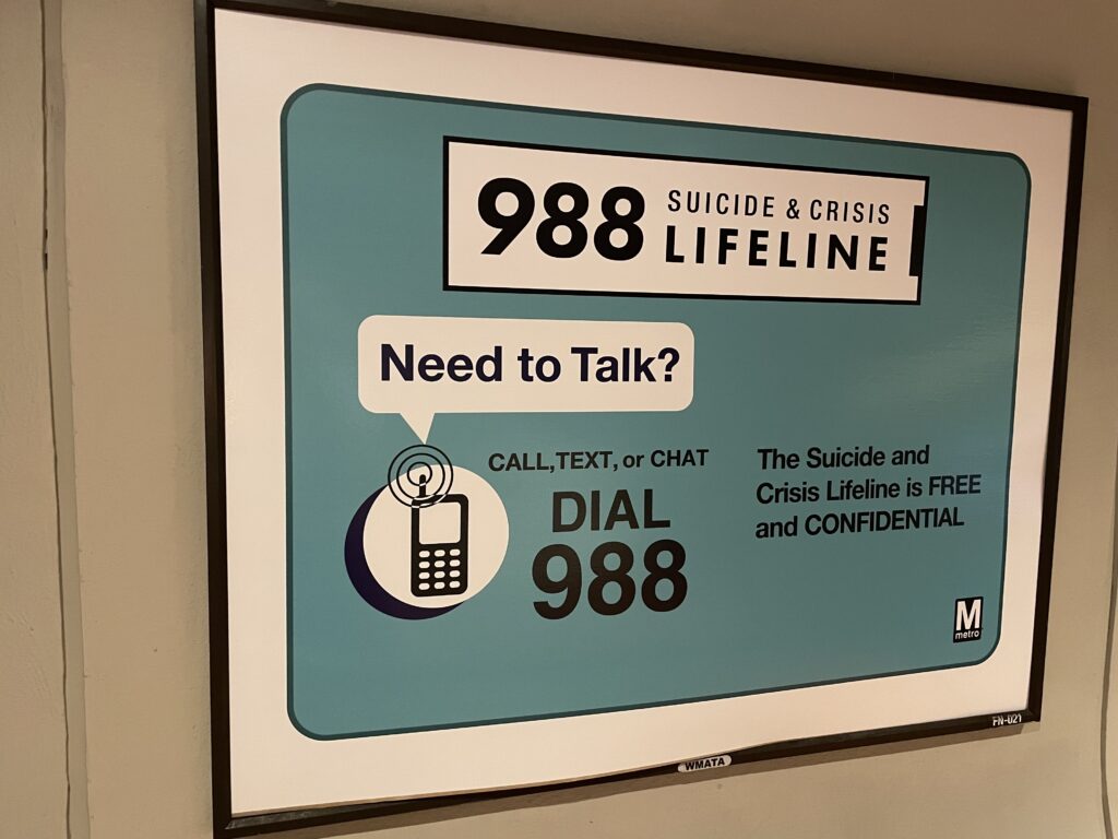 A sign displays resources for those struggling with mental health, a helpline called 988.
