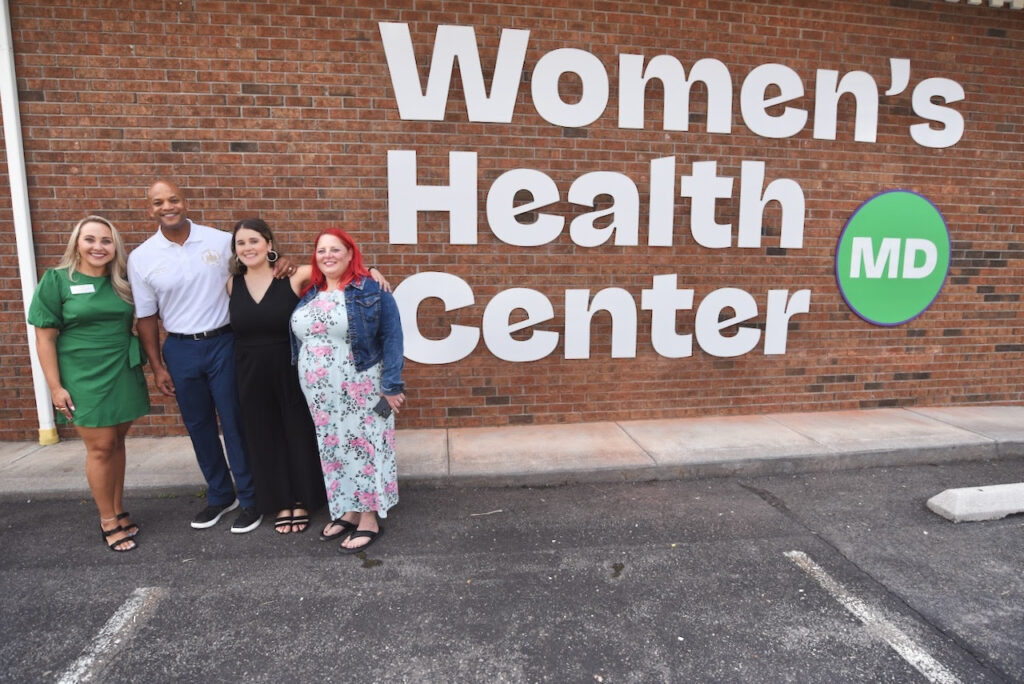 A group of people pose in front of the Women's Health Center of Maryland.