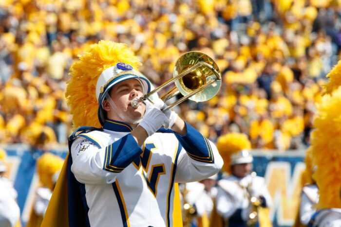 A college band member dressed in white, yellow and blue.