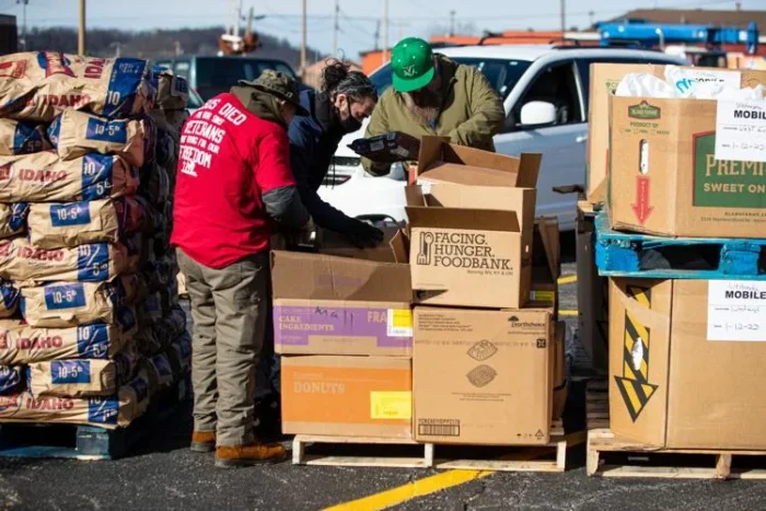 People sort through food items in large containers.