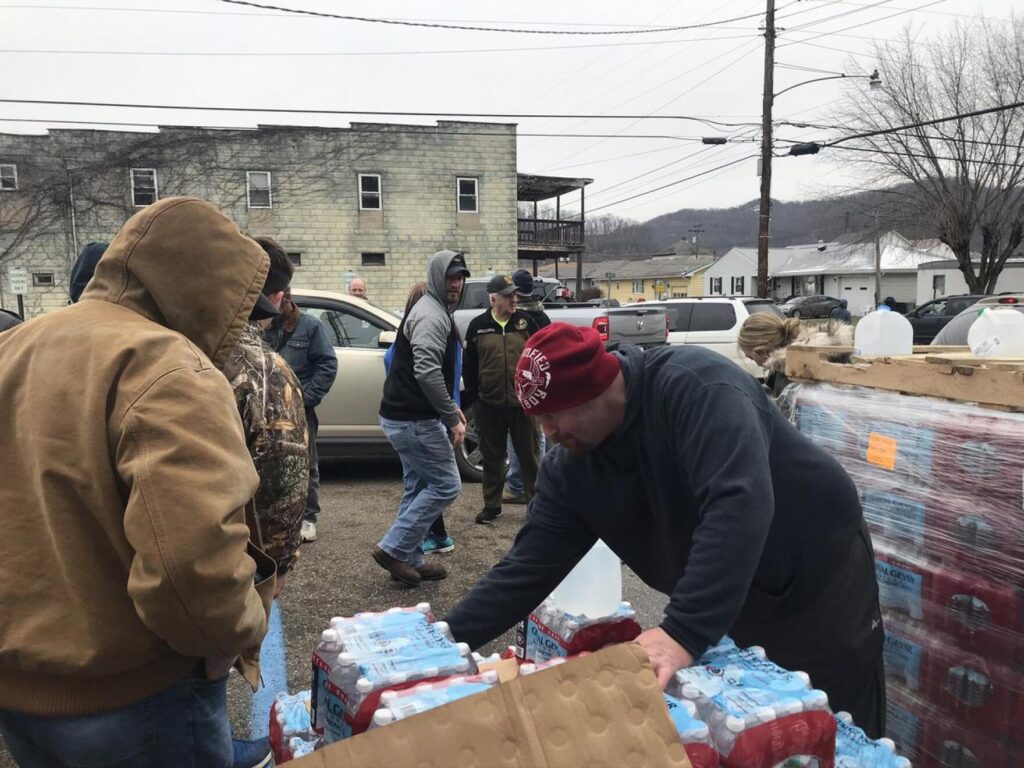A picture of a man distributing bottles of drinking water