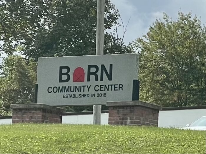 A Large stone sign sits at the top of the hill and Reads BARN community center.