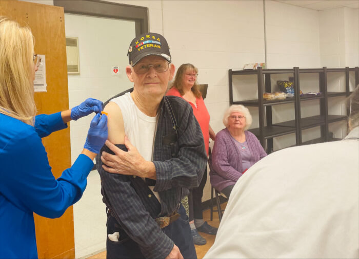 Man wearing a Veterans hat gets a shot in the arm.