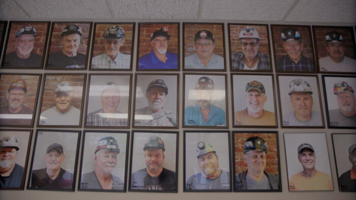 A wall featuring the photographs of dozens of coal miners.