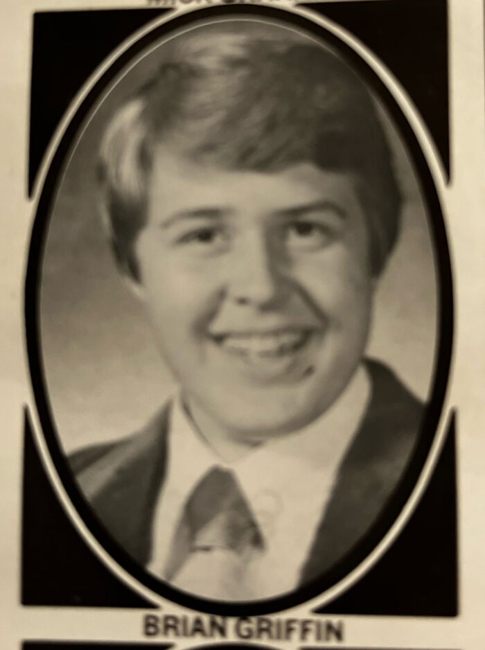 A black and white senior yearbook image of a smiling boy.