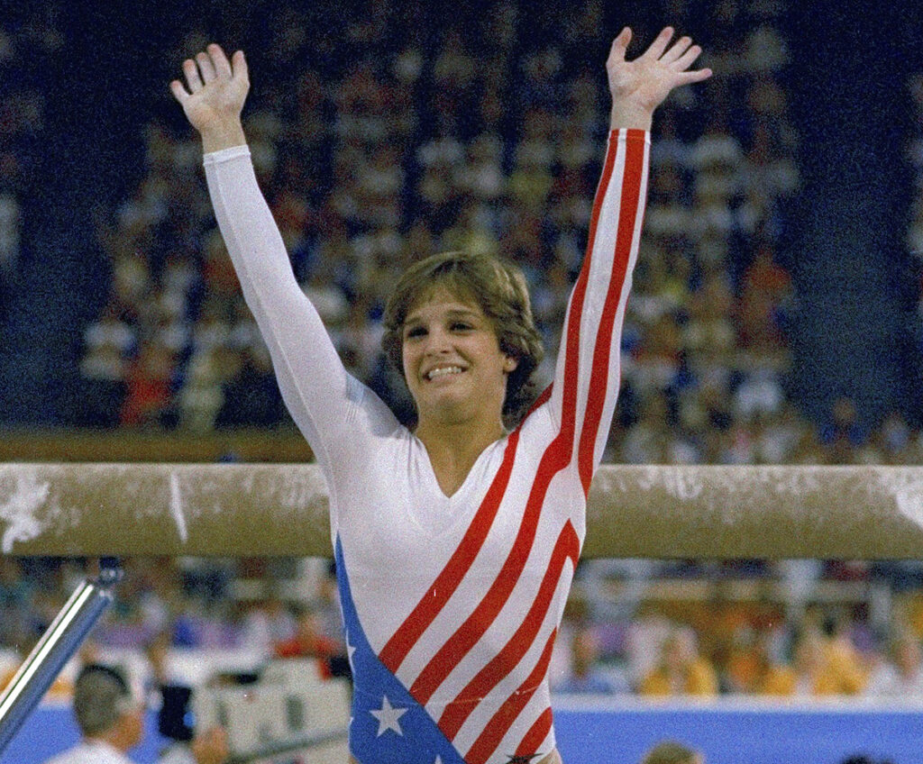 Young woman in gym suit with arms raised