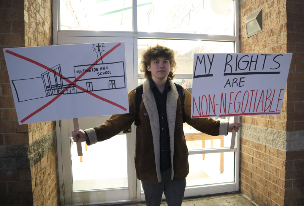 A student holds signs in a protest.