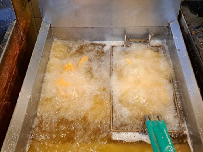 A fryer is shown. Fish simmer in the hot oil.