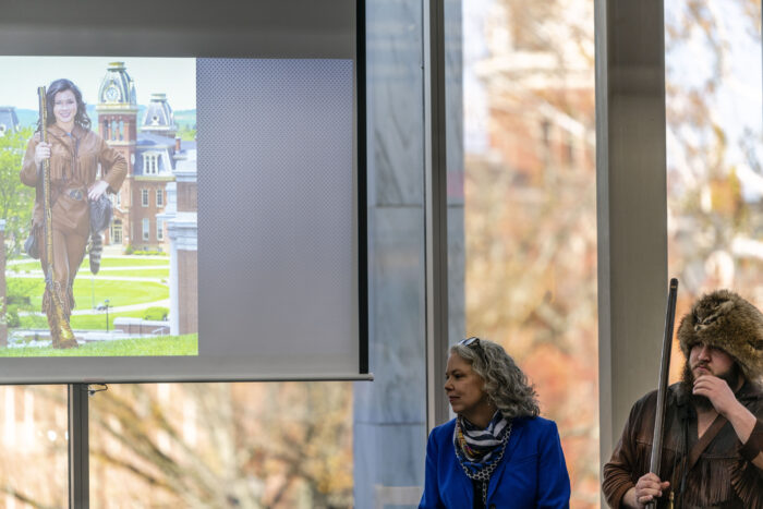 Rosemary Hathaway and Timmy Eads speaking at an event at WVU during Mountaineer Week in 2019. Pictured in the slideshow is Rebecca Durst who was the mascot in 2009.