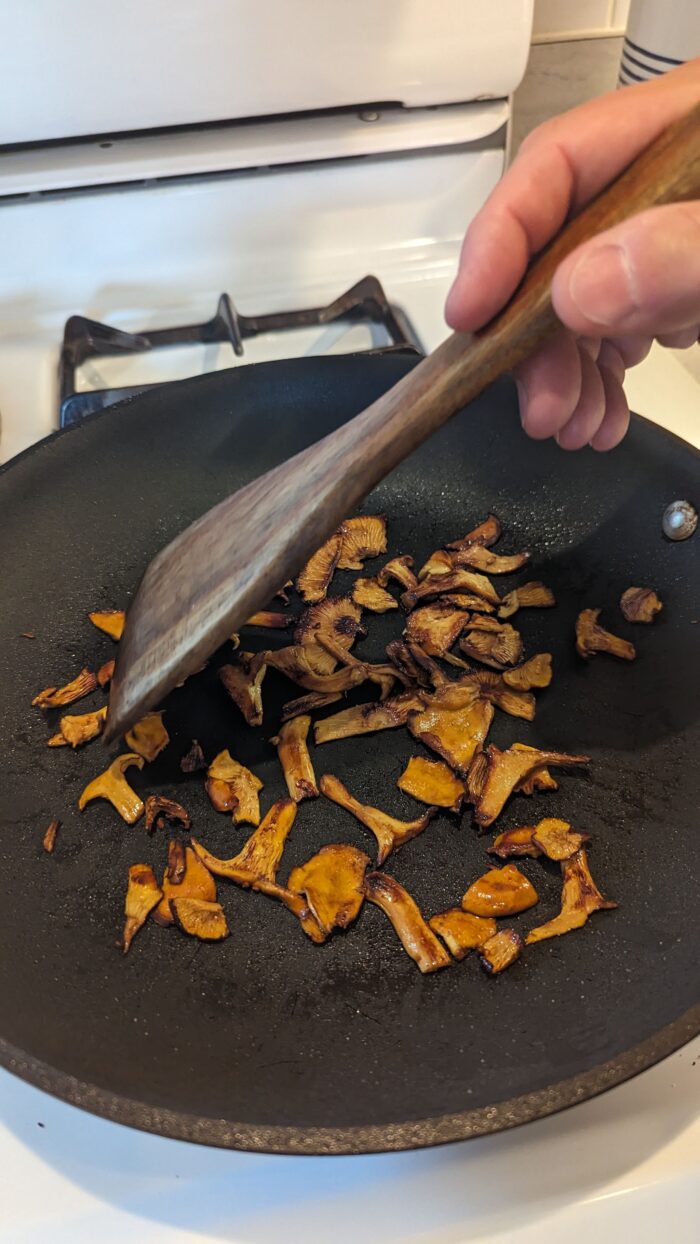 Mushrooms are seen cooking in a pan on a stove top.
