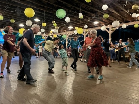 A group of people square dance together.