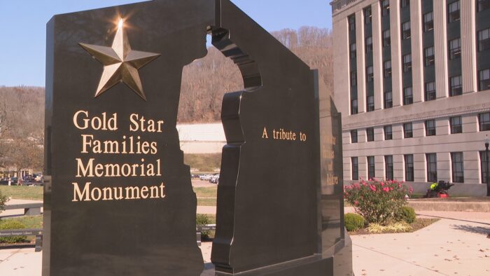 The back of the Gold Star Families Memorial Monument in Charleston, WV. It shows the shape of a soldier saluting. A large gold star shimmers in the sun.