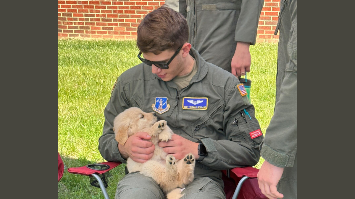 A man in uniform holding a puppy