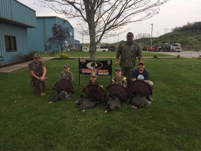 Young people in hunting gear with harvested wild turkey's.