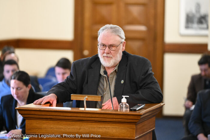 Man in a suit jacket and shirt with gray hair speaks at a podium