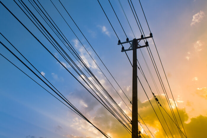 Silhouette, Electricity transmission lines and power poles Sunshine twilight sky backdrop.