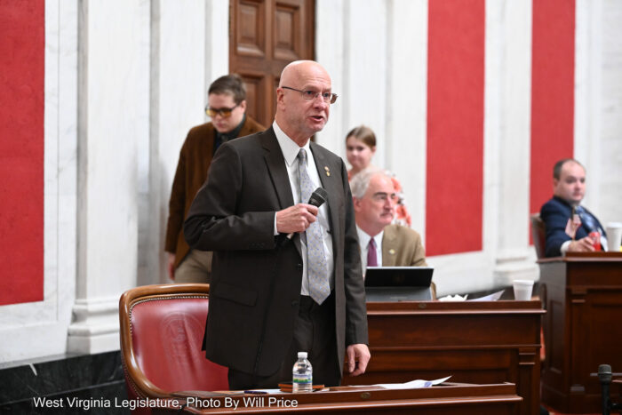 Bald man in a dark suit holding a microphone