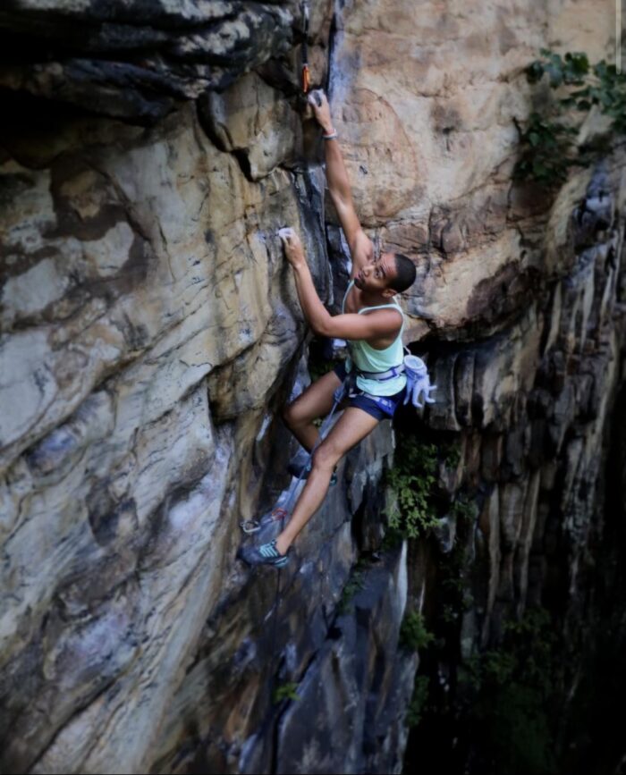 A young man climbs a rock face.