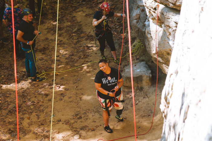 Three people ready themselves for rock climbing.