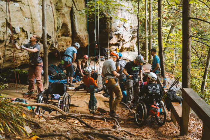 Several climbers, and many in wheelchairs, prepare to rock climb.