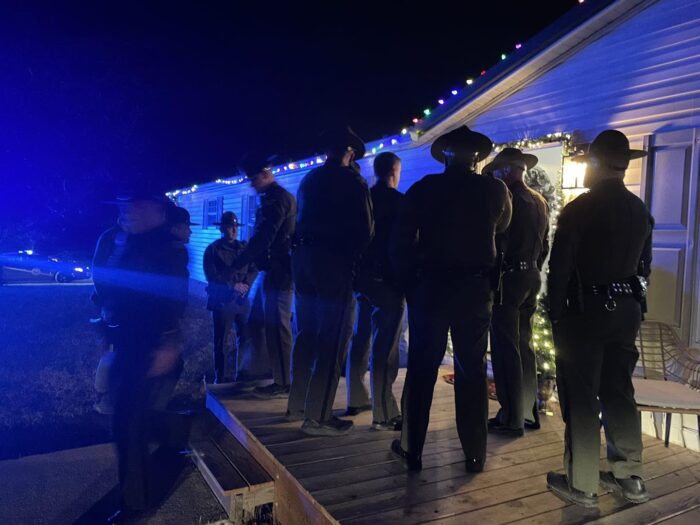 Several people in police uniform in front of a home/