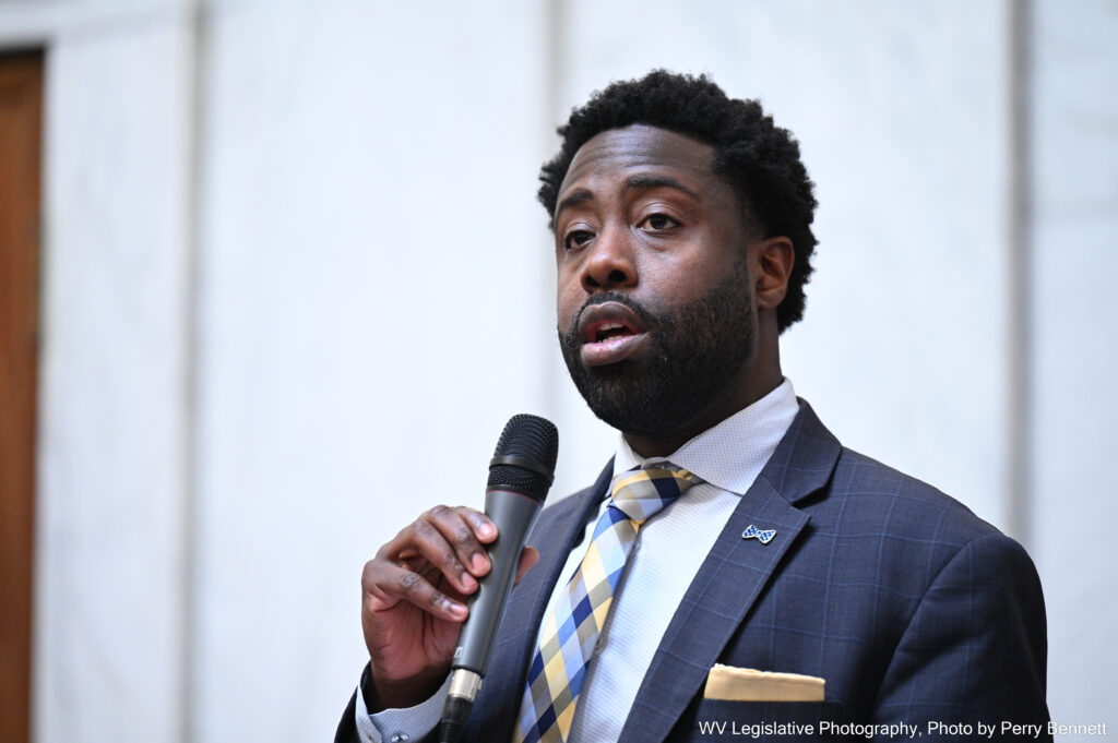 Close shot of black man in blue suit speaking into microphone