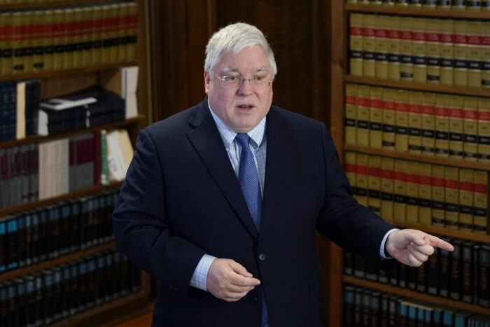 man in a suit and tie in front of library shelves with law books