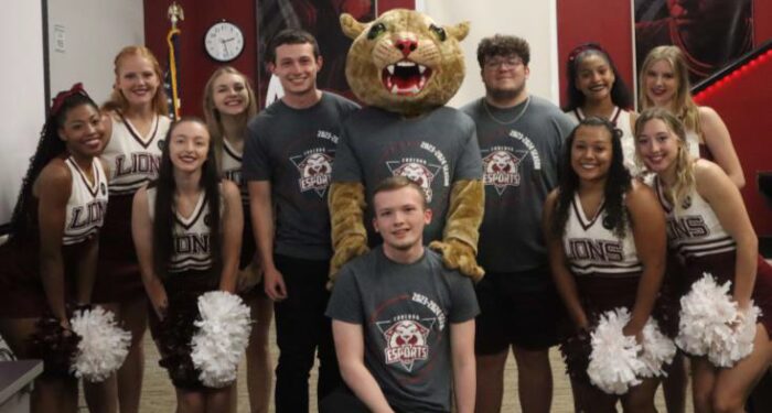 A group of college students and cheerleaders pose with a school's mascot.