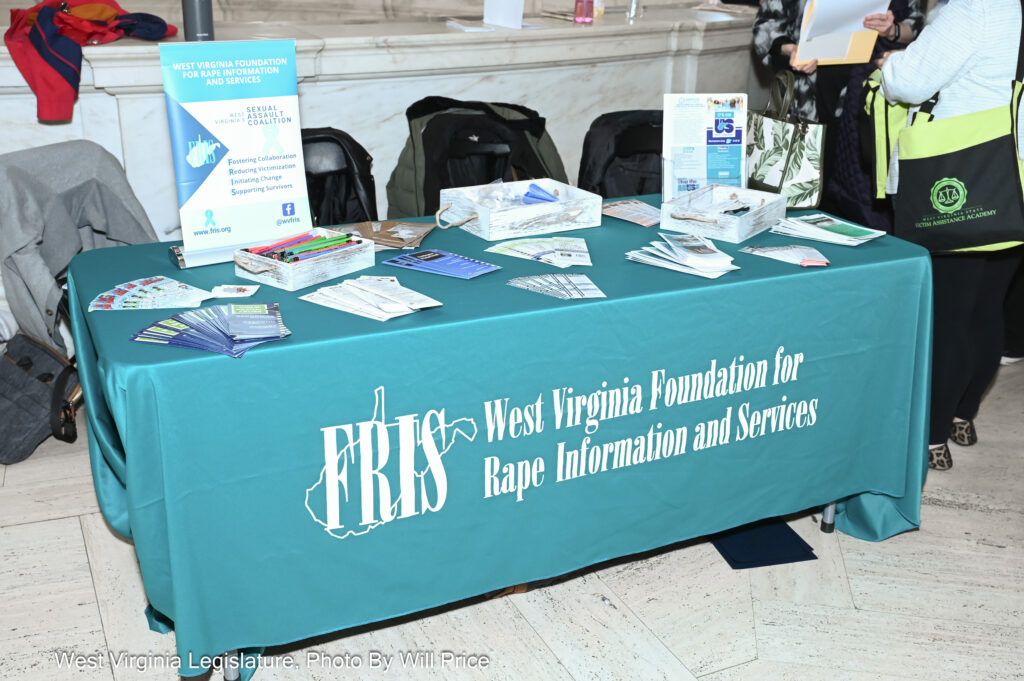 A turquoise tablecloth drapes a table laden with pamphlets and memorabilia with helpful information about handling sexual assault.