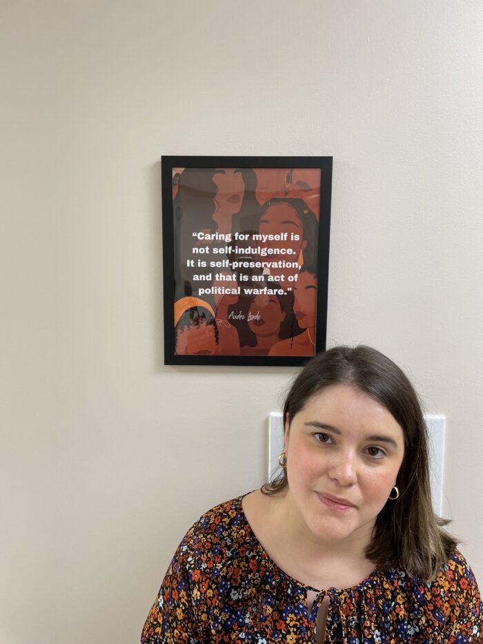 Katie Quiñonez stands before a framed quote by Audra Lord, which hangs on the wall of the Women’s Health Center of Maryland. The quote reads, "Caring for myself is not self-indulgence. It is self-preservation, and that is an act of political welfare."