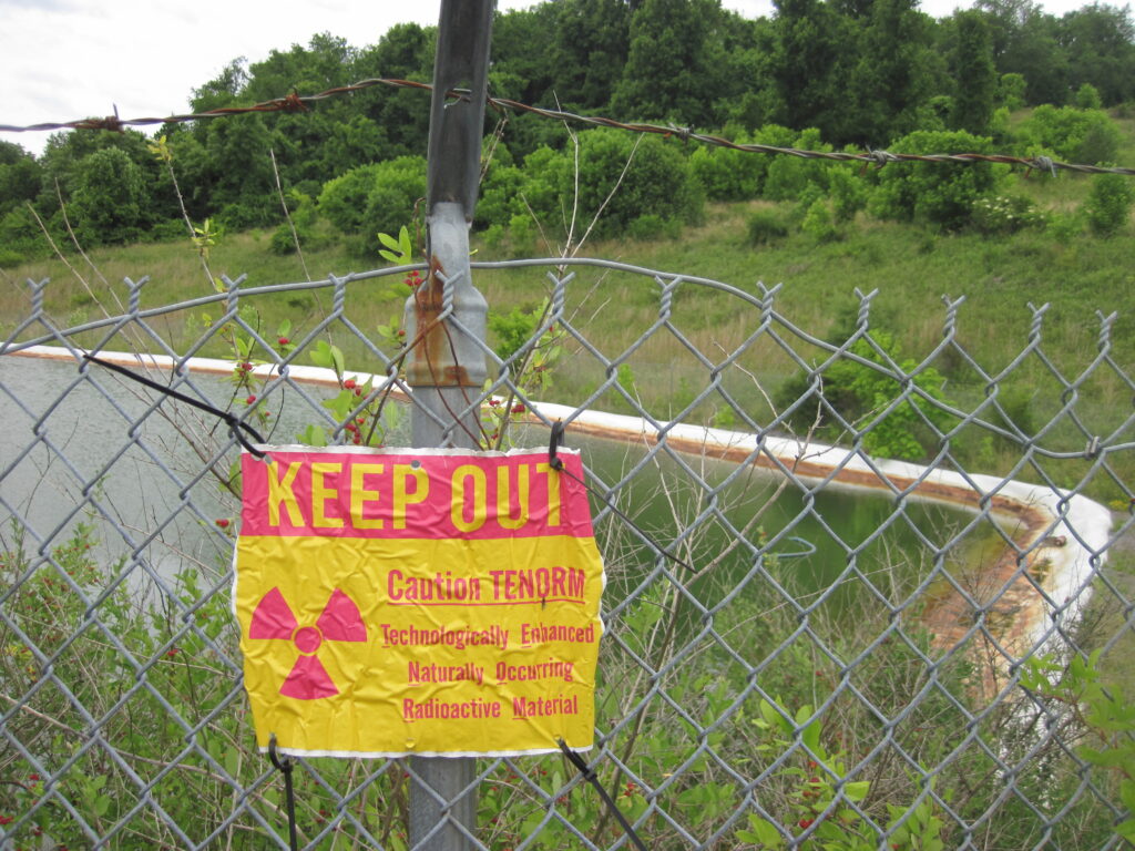 A chain link fence is shown. On the fence is a sign that reads, "Keep Out," and there's a biohazard symbol.