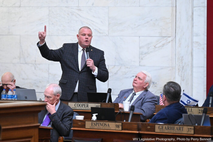 Husky, bald man with pointed finger speaking to several others.