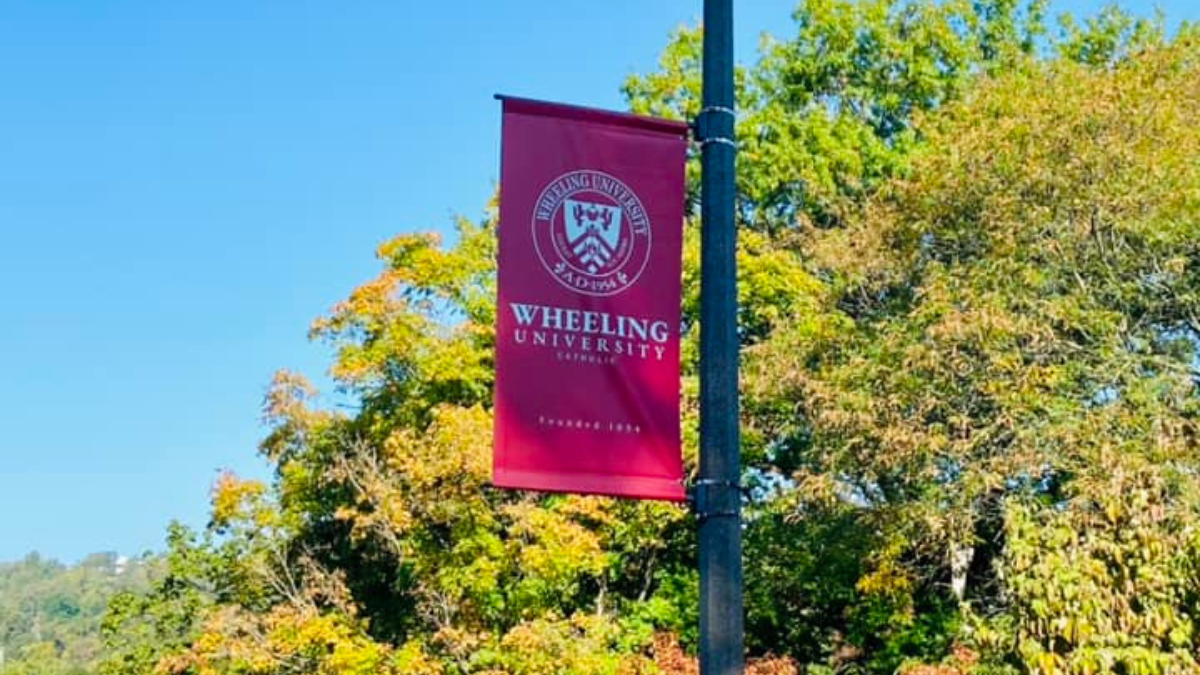 Wheeling University's emblem is shown on a flag attached to a lamp post.