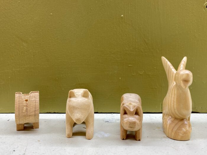 Four wood carvings are on display, all appear to be different animals.