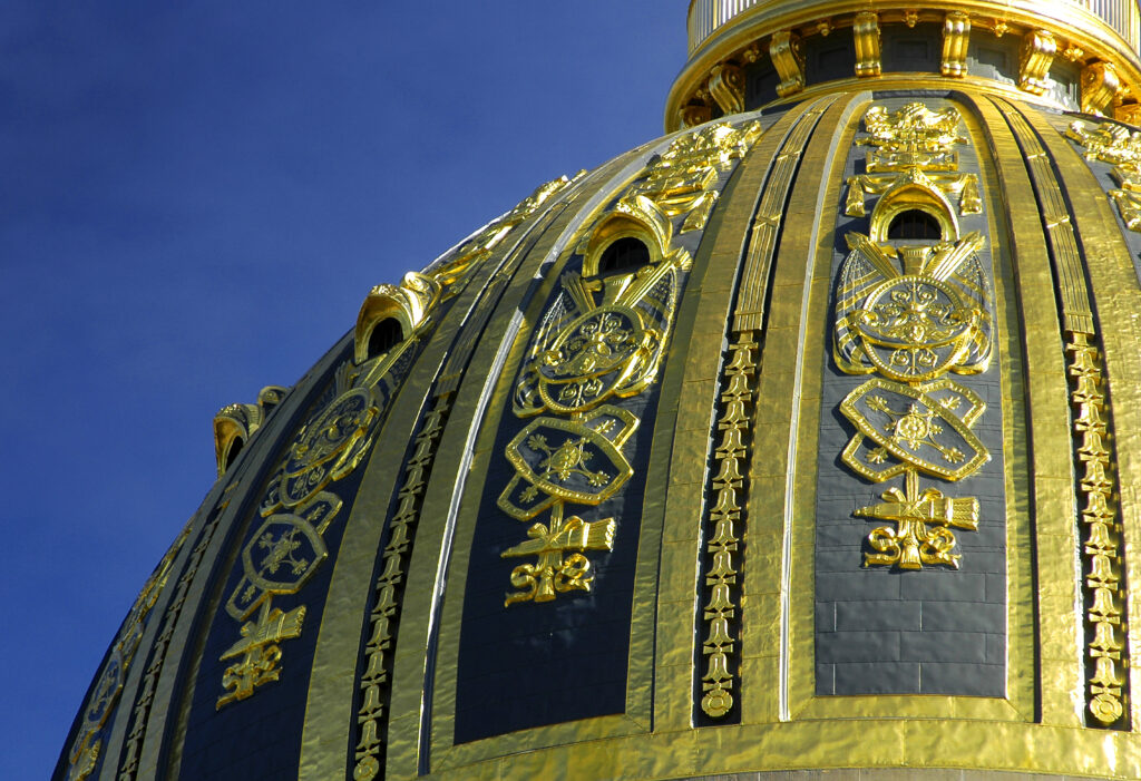 The curve of a dome takes up most of the frame, with a blue sky taking up the top left corner. Gold detailing dominates the dome's profile.