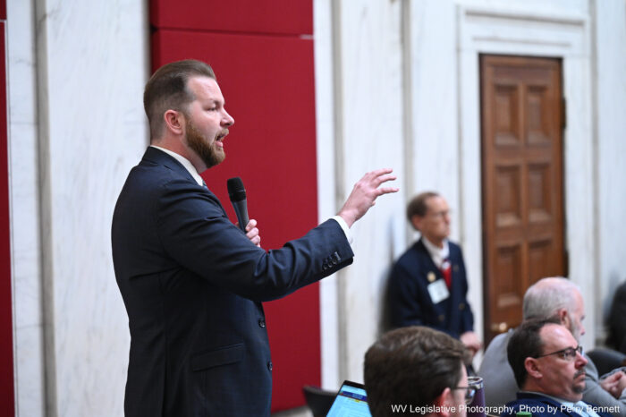 Tall man with beard in suit speaking to large room of people