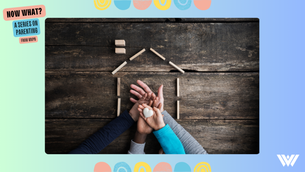 Top view of a family of four placing hands one on top of the other in a conceptual image of love, togetherness and safety. The hands are placed inside of the outline of a home made from small wooden blocks, and all is placed on a dark wood background. The image is bordered by a blue gradient with pastel colored circles above and below. In the top left of the frame are the words "Now What? A Series On Parenting" and in the bottom right is the WVPB logo.